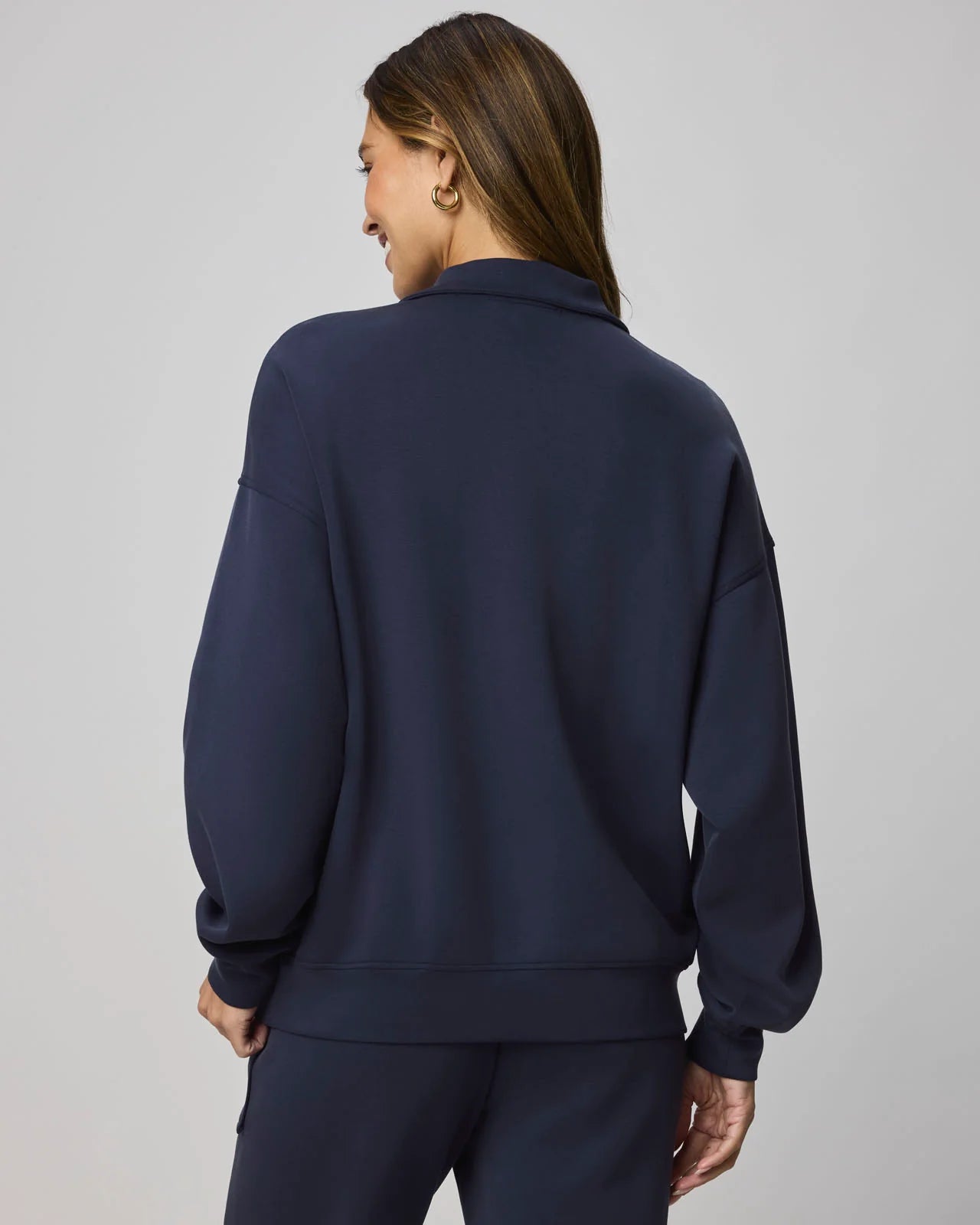 Person wearing a navy blue tracksuit against a gray background