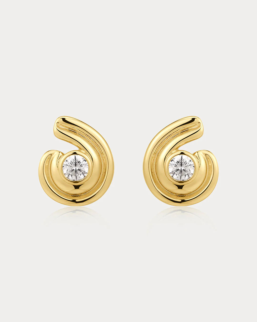 Gold earrings with diamond centers on a light gray background
