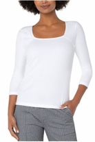 Woman wearing a white long-sleeve top and plaid pants on a white background