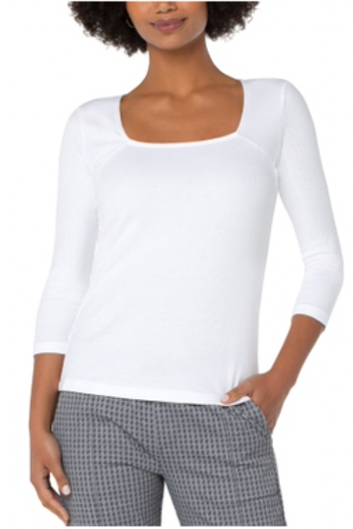 Woman wearing a white long-sleeve top and plaid pants on a white background