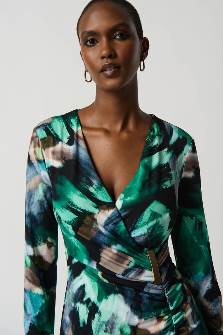 Model wearing a green and black patterned dress against a white background