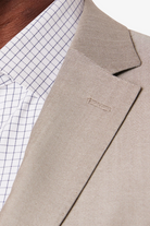 Close-up of a beige blazer with a brand logo on a white background