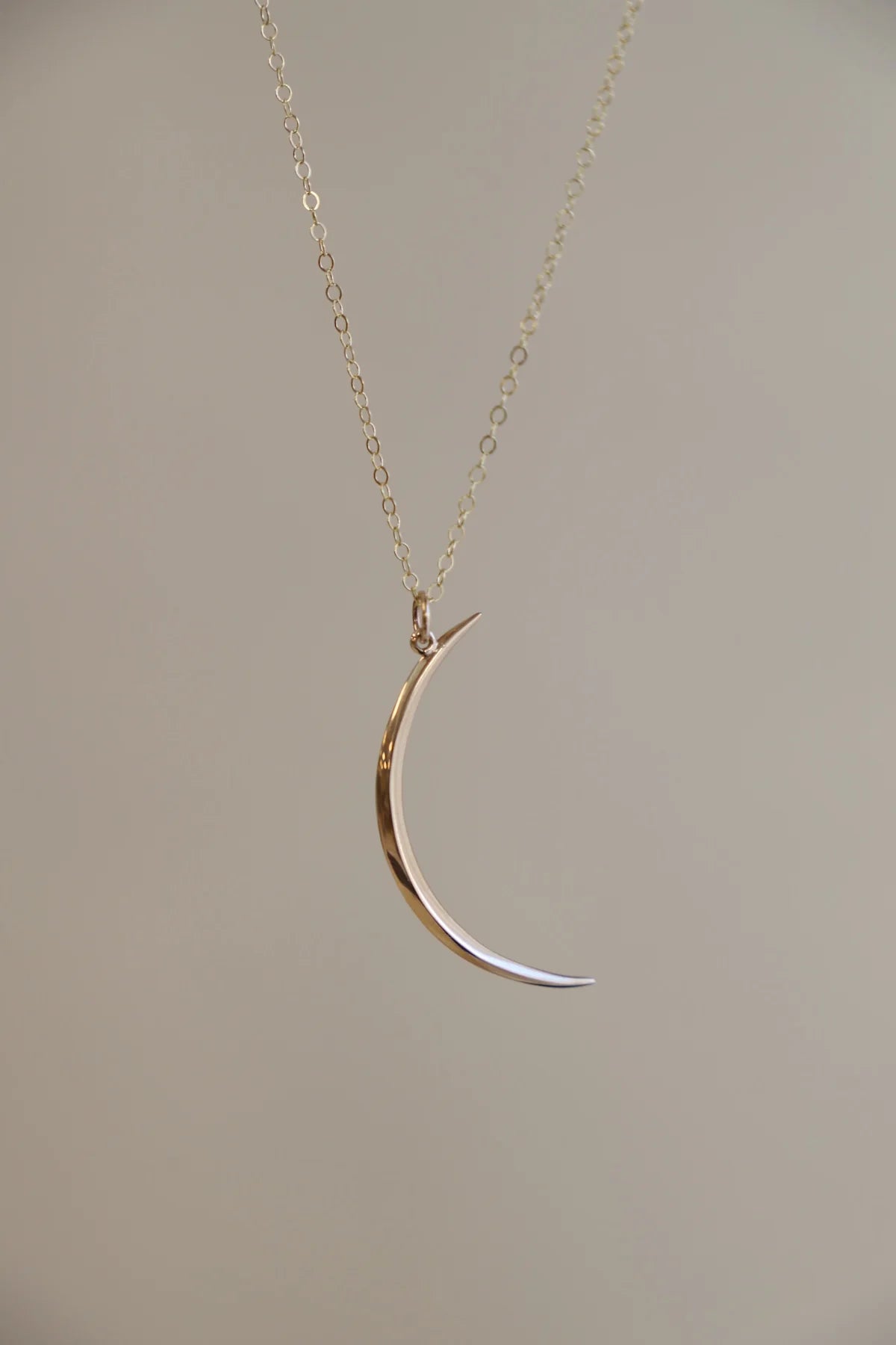Gold and silver crescent moon necklace on a plain background