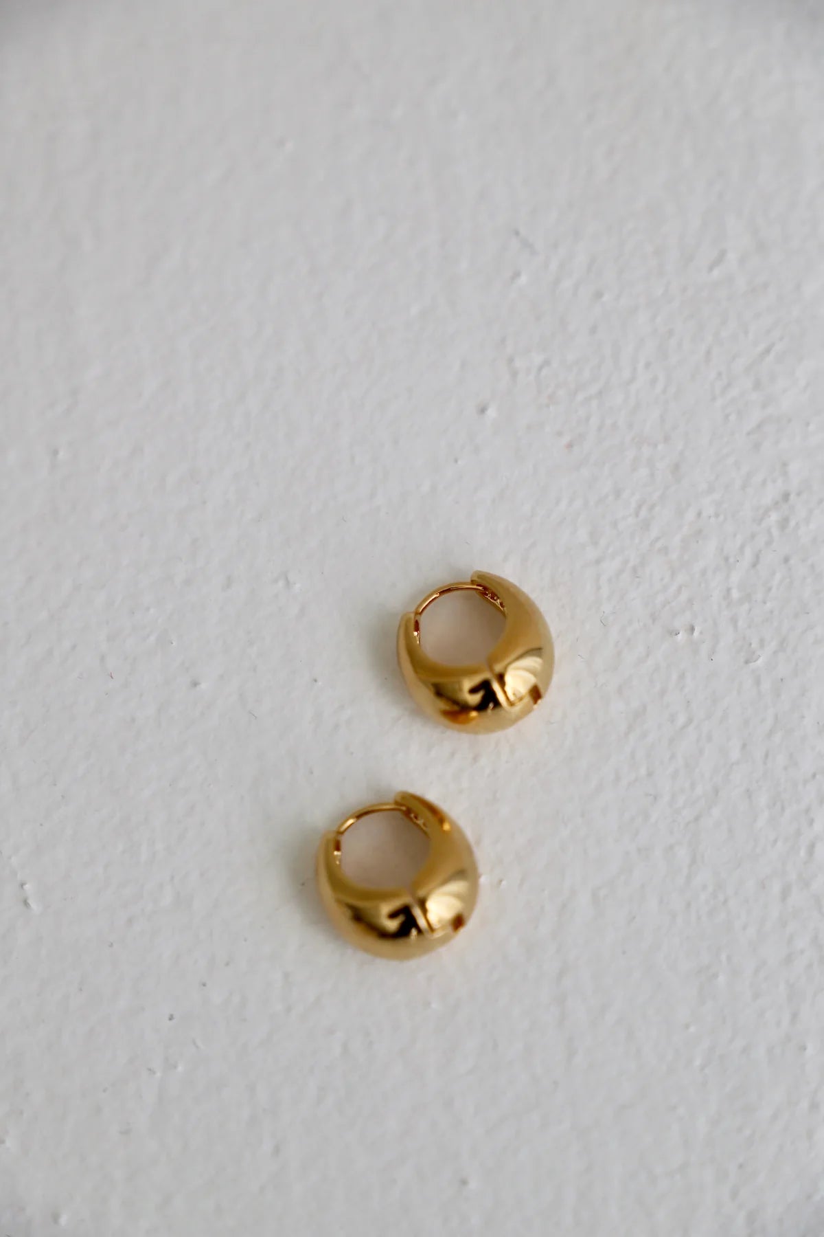 Gold hoop earrings on a light gray background