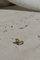 Gold earring with heart-shaped design on a light surface