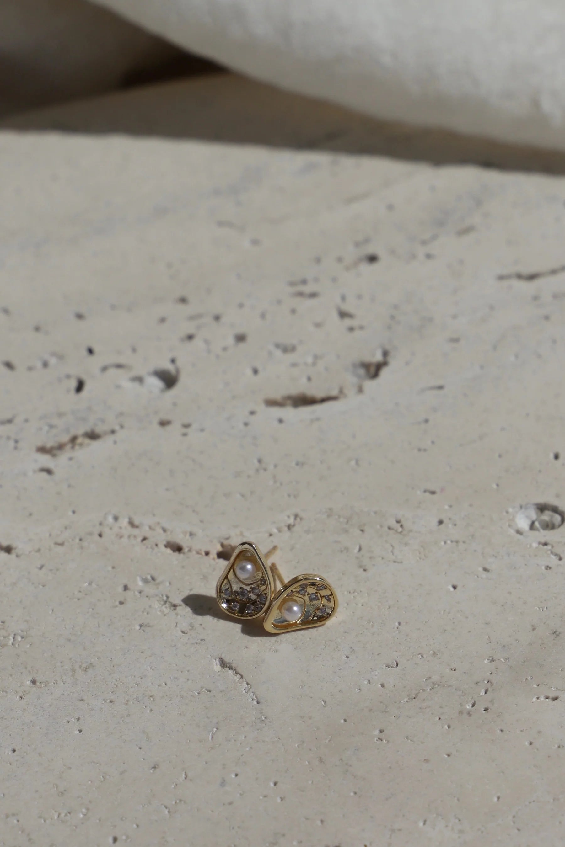 Gold earring with heart-shaped design on a light surface