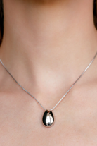 Silver necklace with a black pendant on a person's neck