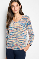 Woman wearing a colorful patterned top against a plain background