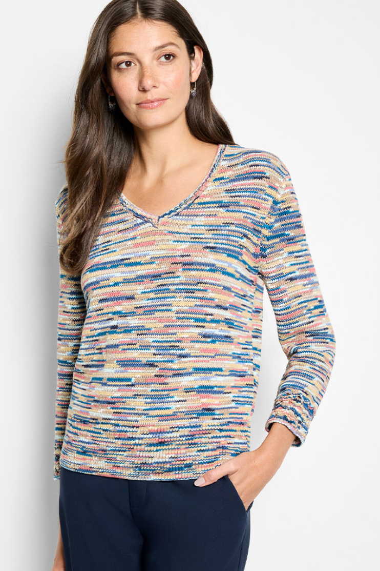 Woman wearing a colorful patterned top against a plain background
