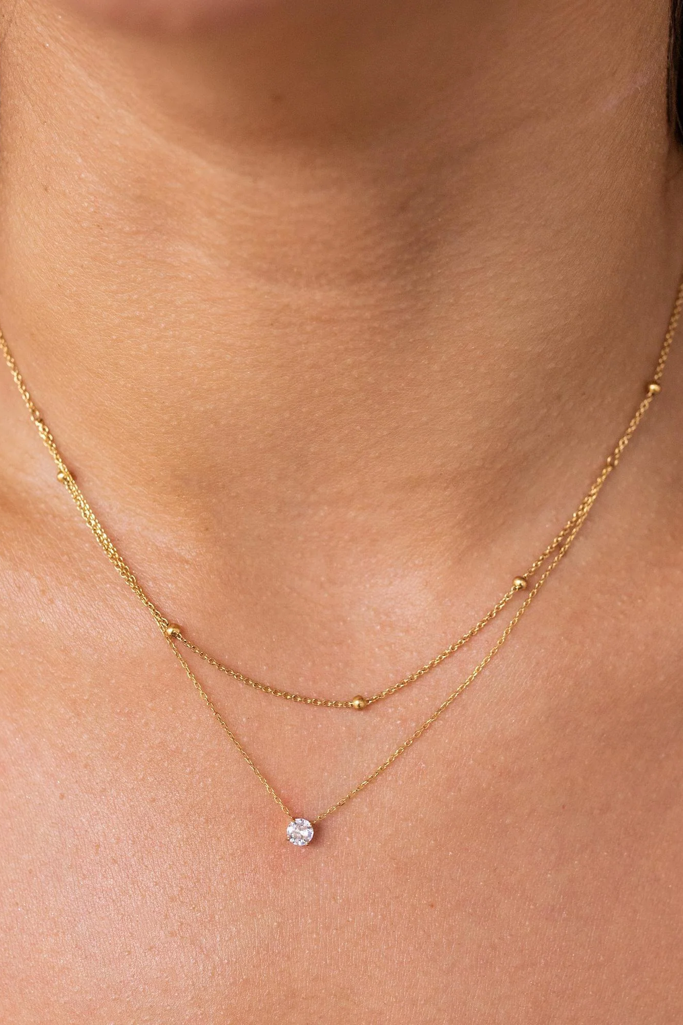 Gold necklace with a small pendant on a person's neck