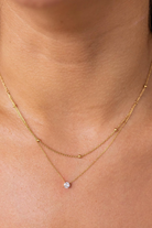 Gold necklace with a small pendant on a person's neck