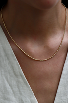 Gold necklace on a person wearing a light-colored top