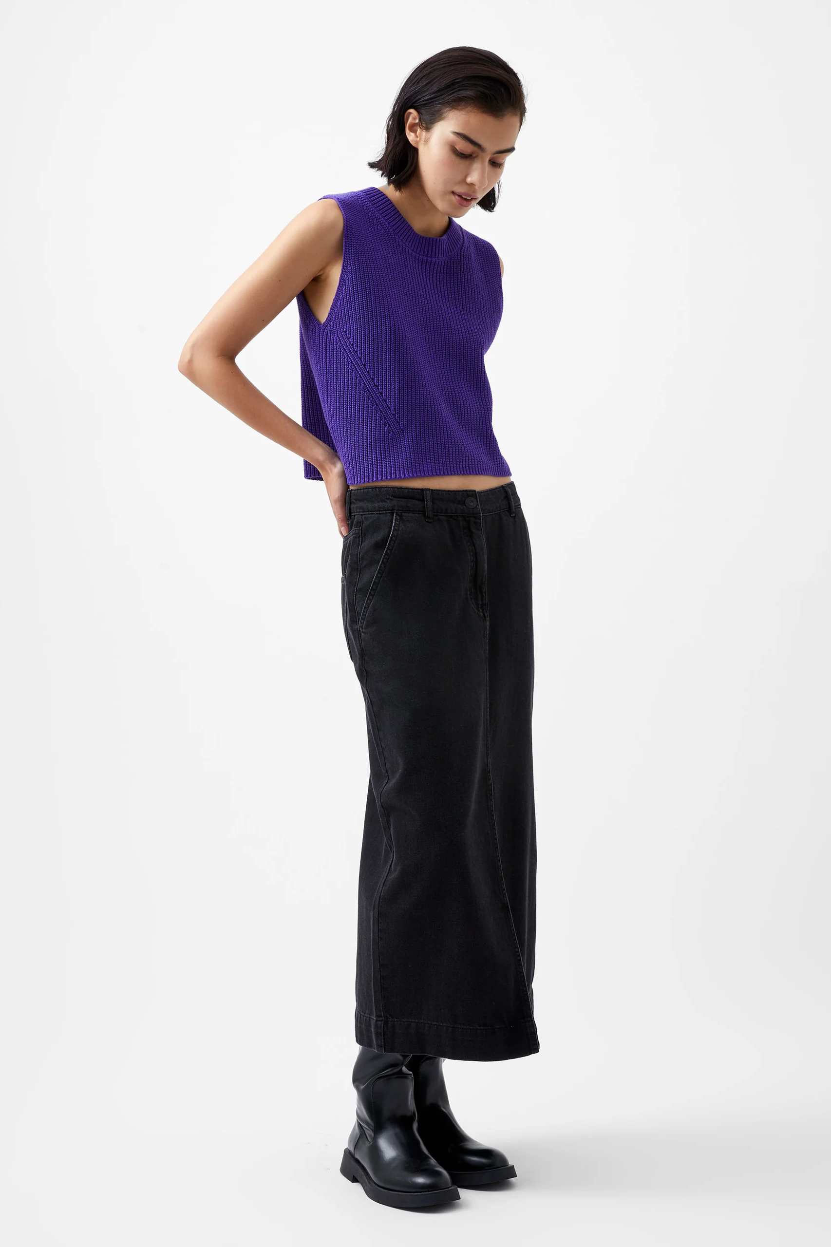 Woman wearing a purple sleeveless top and black pants on a white background