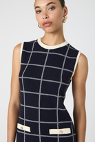 Woman wearing a sleeveless dress with a grid pattern on a white background