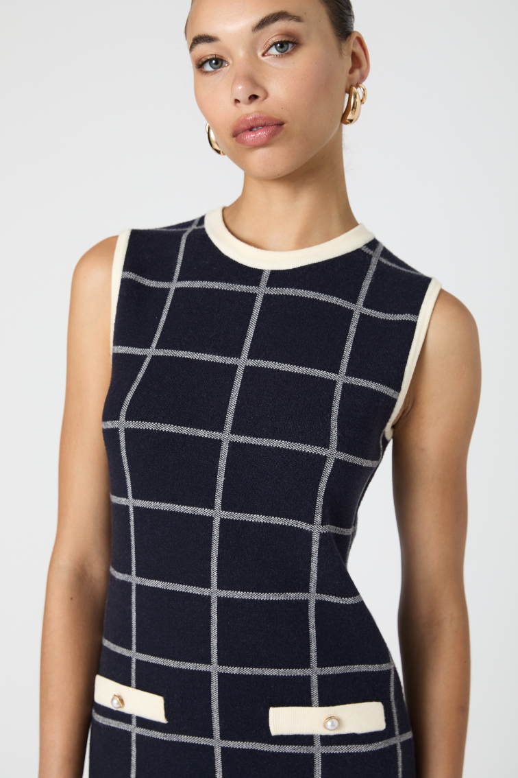 Woman wearing a sleeveless dress with a grid pattern on a white background
