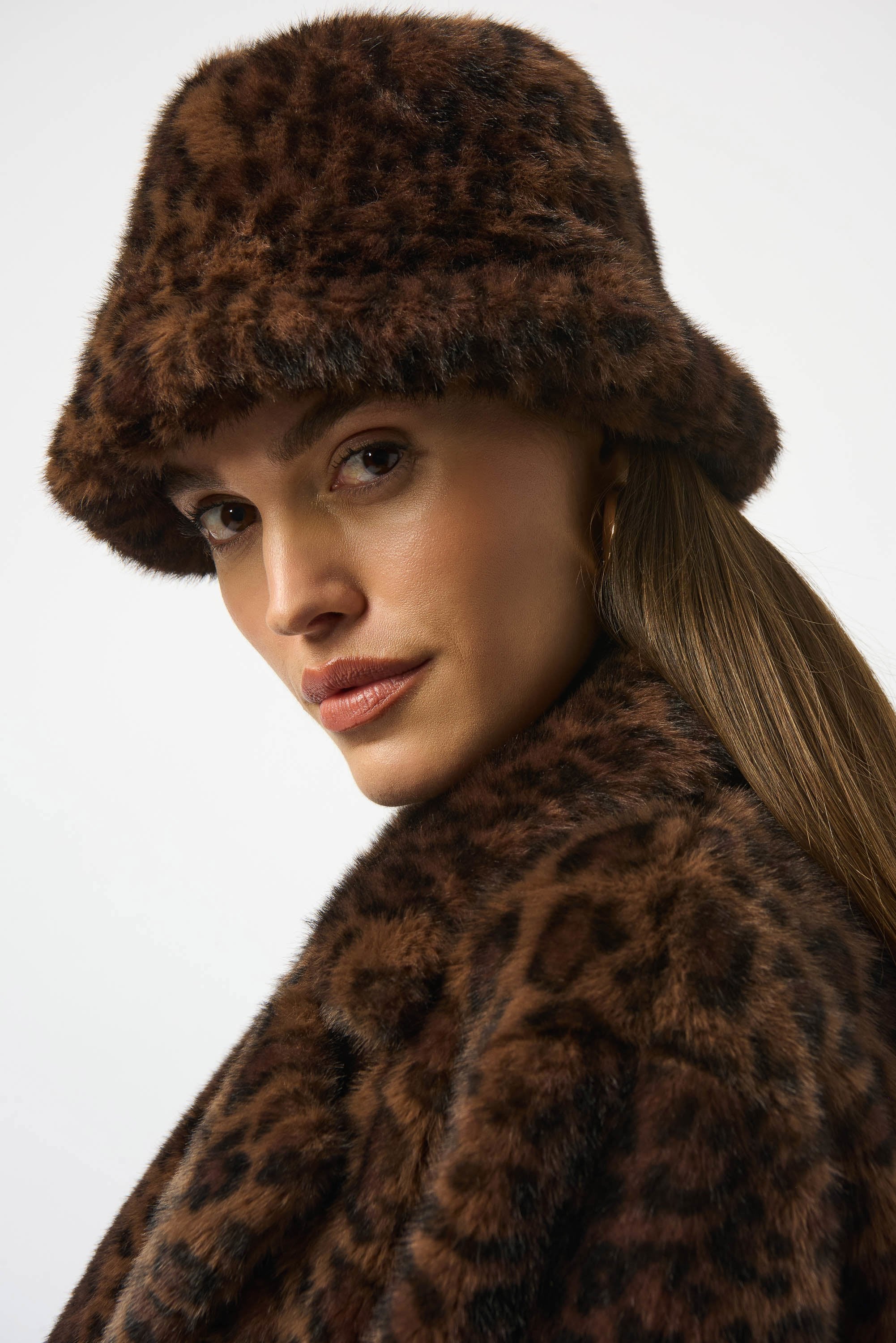 Woman wearing a leopard print fur coat and hat on a white background