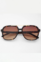 Sunglasses with tortoiseshell frame and brown lenses on a white background
