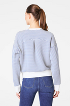 Person wearing a striped sweater and blue jeans on a white background