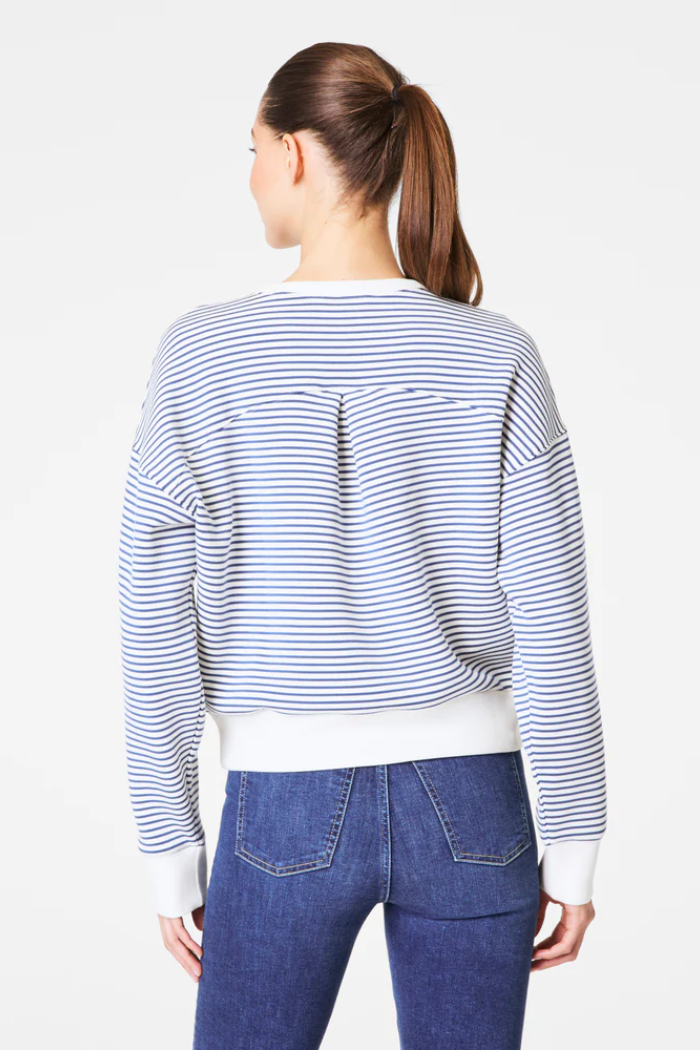 Person wearing a striped sweater and blue jeans on a white background