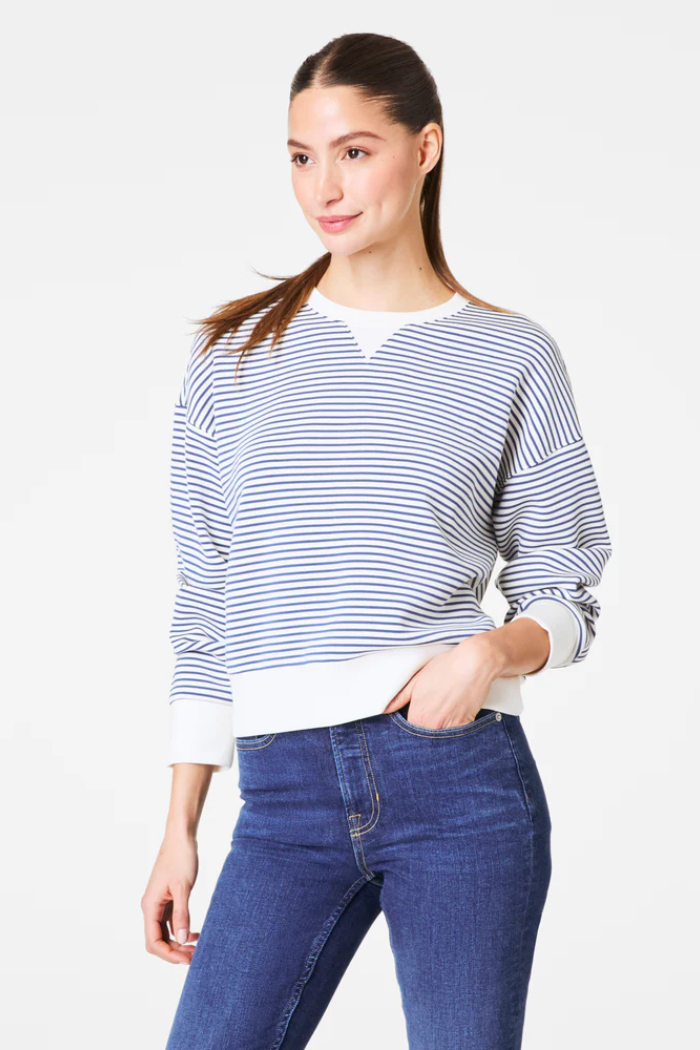 Woman wearing a striped sweater and blue jeans on a white background