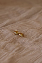 Gold earring on a textured beige fabric background