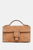 Brown suede handbag with a buckle on a light gray background