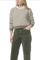 Woman wearing a striped sweater and green pants on a white background