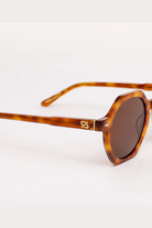 Sunglasses with tortoiseshell frame and dark lenses on a white background