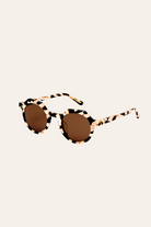 Round sunglasses with a leopard print frame on a beige background