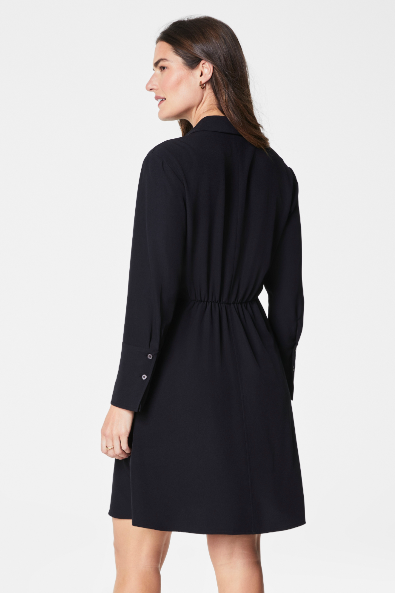 Woman wearing a black dress with buttons on a white background