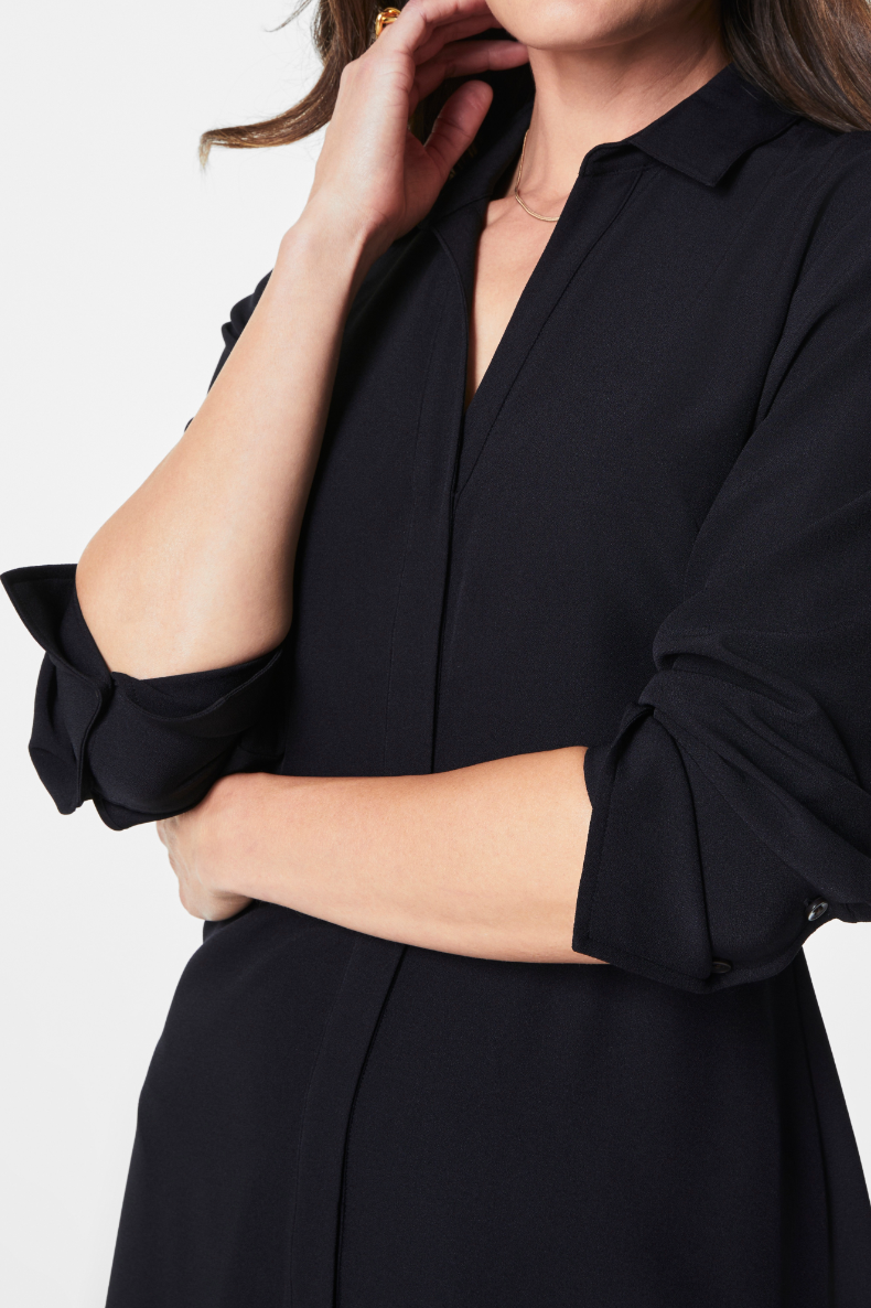 Person wearing a black dress with rolled-up sleeves on a white background