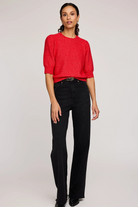 Woman wearing a red sweater and black pants on a white background
