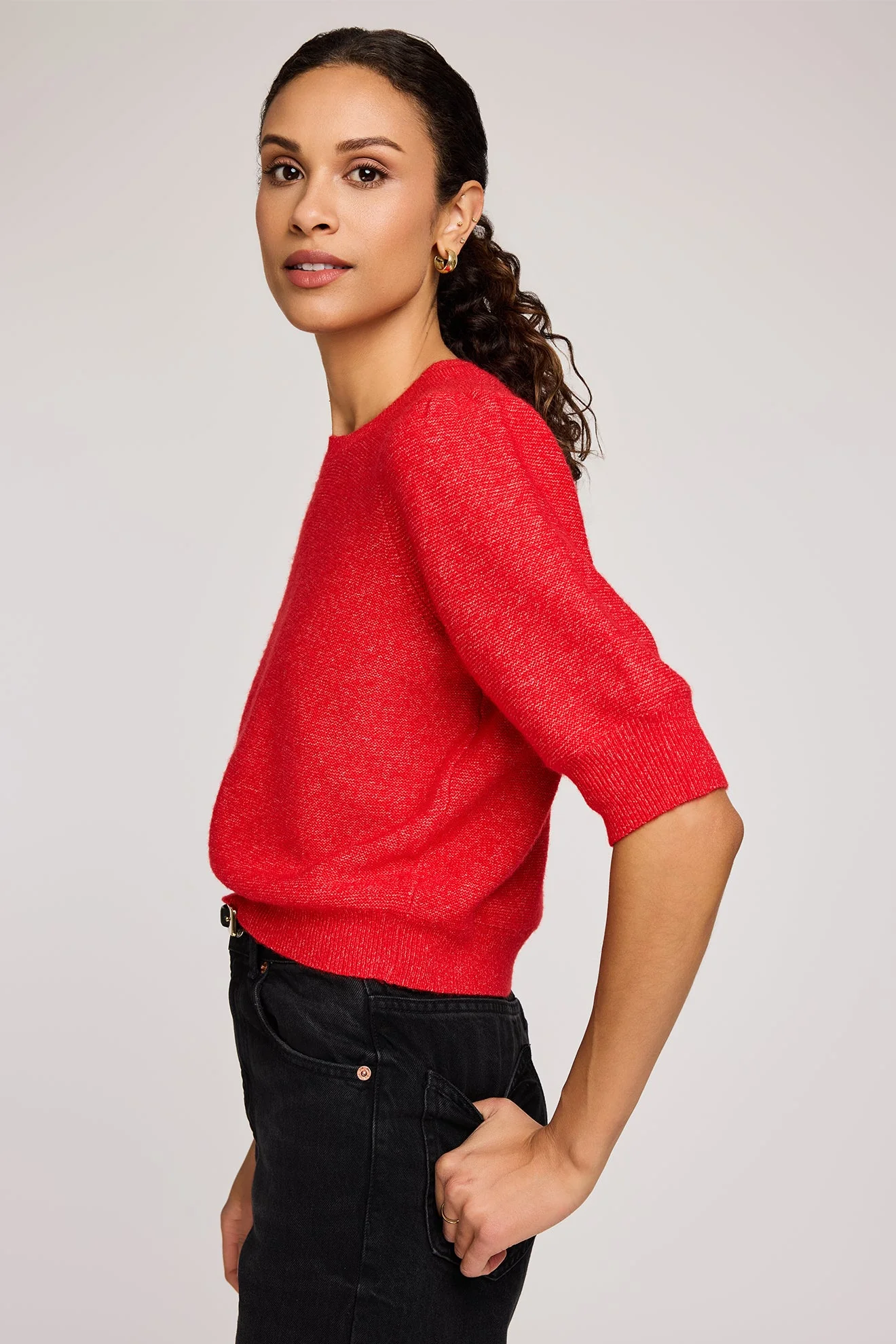 Woman wearing a red sweater against a plain background