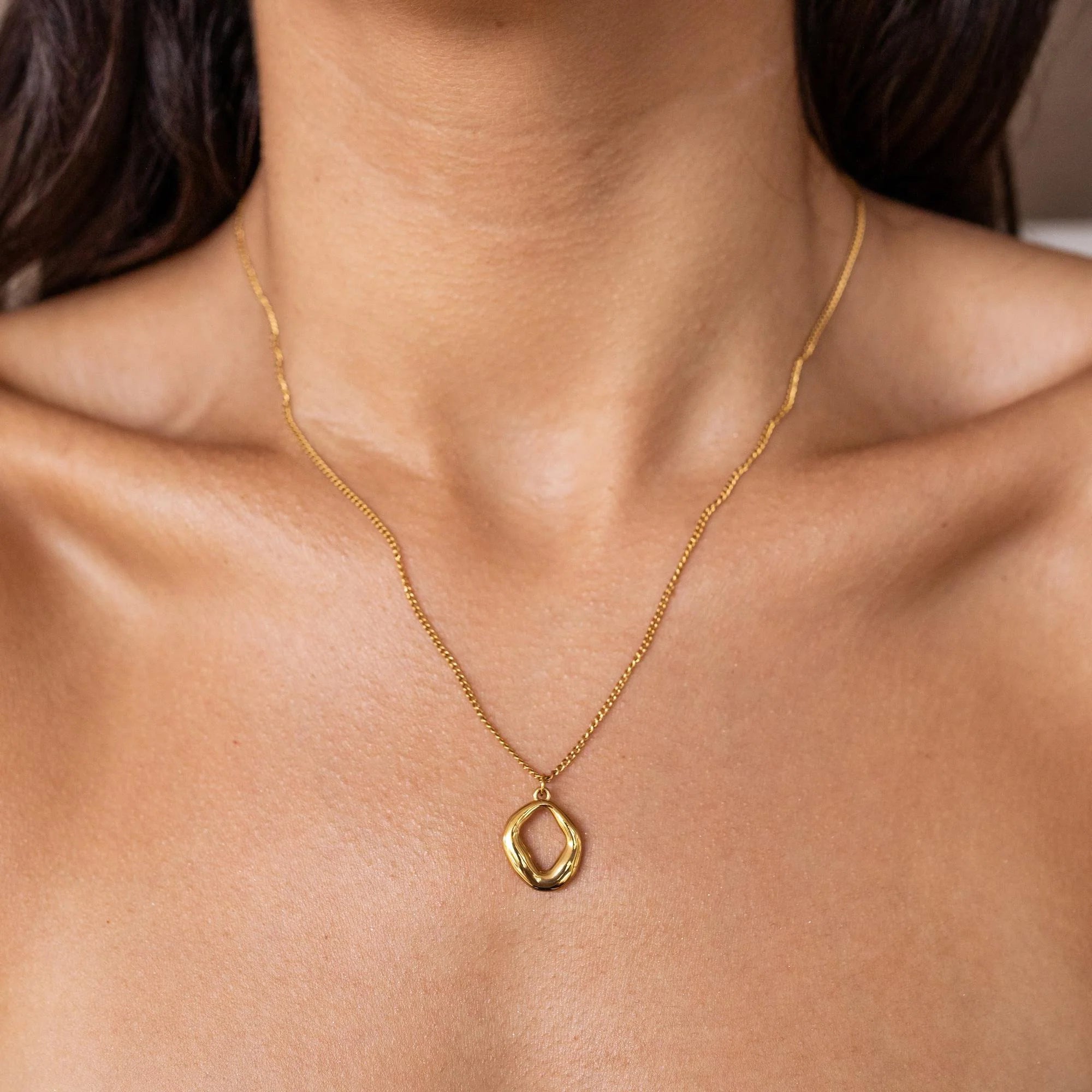 Gold necklace with a pendant on a person's neck