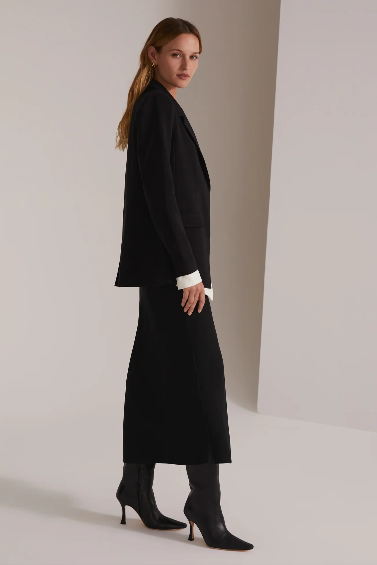 Woman wearing a black coat and high heels on a plain background