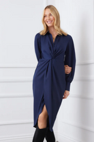 Woman wearing a navy blue dress with a knot detail against a white background