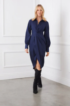 Woman wearing a navy blue dress with a white wall background