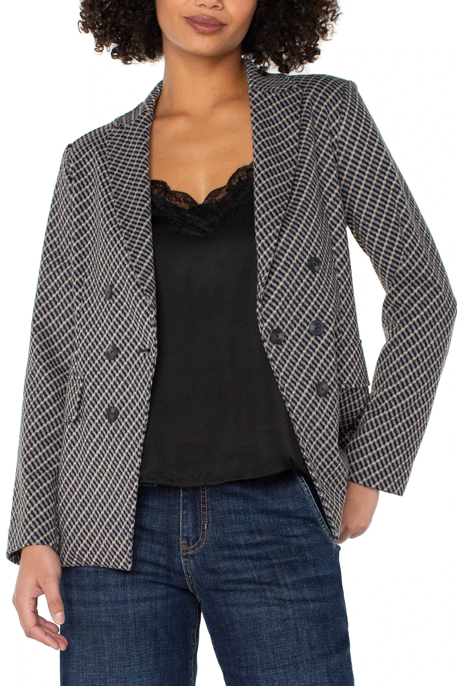 Woman wearing a checkered blazer over a black top and blue jeans on a white background
