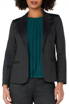 Person wearing a dark gray blazer over a teal top on a white background