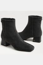 Pair of black ankle boots on a light gray background
