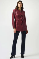 Woman wearing a burgundy jacket and dark pants on a white background