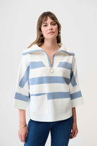 Woman wearing a white and blue striped sweater on a plain background