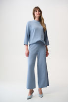 Woman wearing a light blue outfit with wide-leg pants on a white background