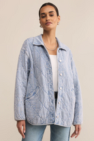 Woman wearing a light blue quilted jacket on a beige background