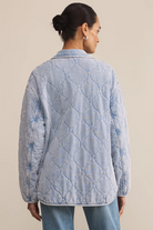 Woman wearing a quilted denim jacket on a beige background