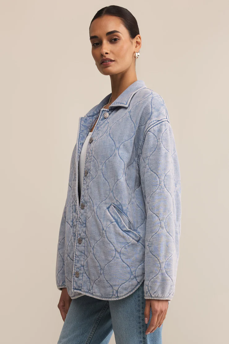 Woman wearing a light blue quilted jacket against a beige background