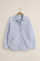 Quilted denim jacket on a hanger against a beige background