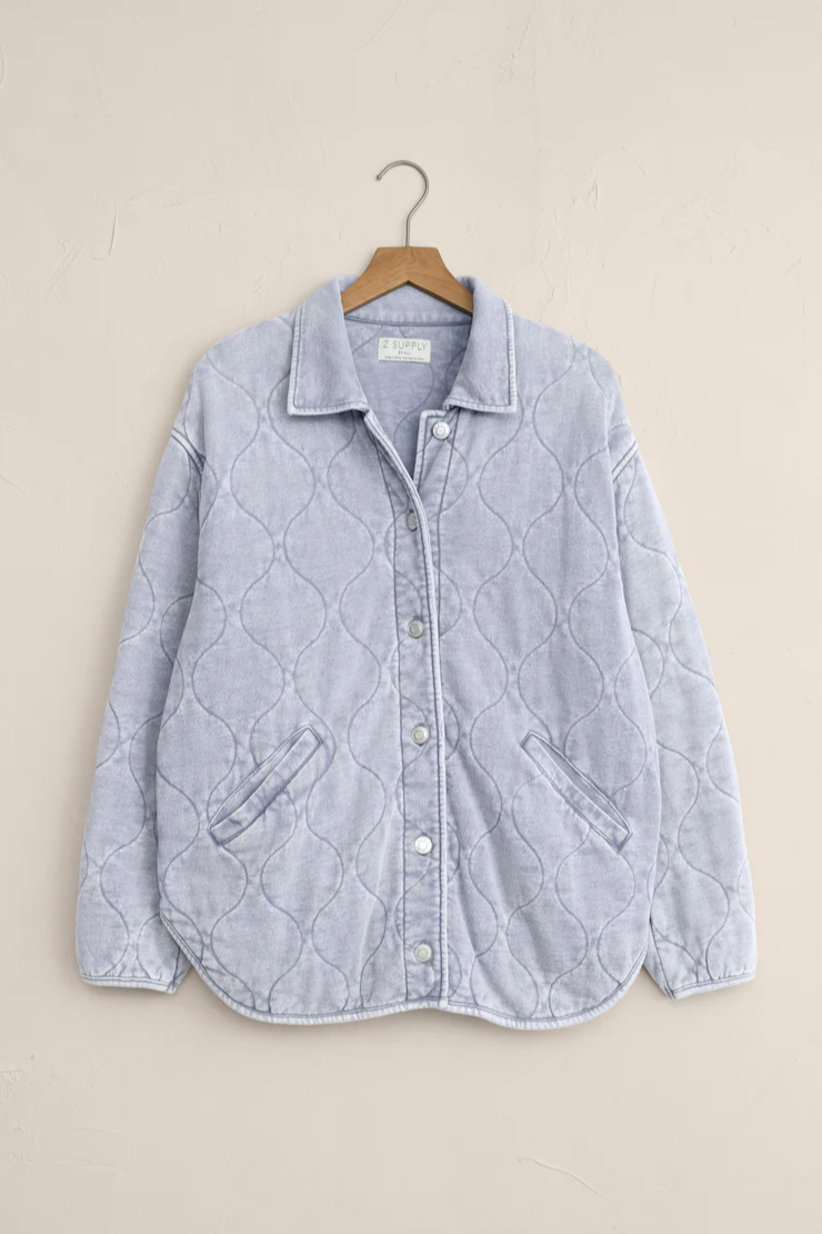Quilted denim jacket on a hanger against a beige background