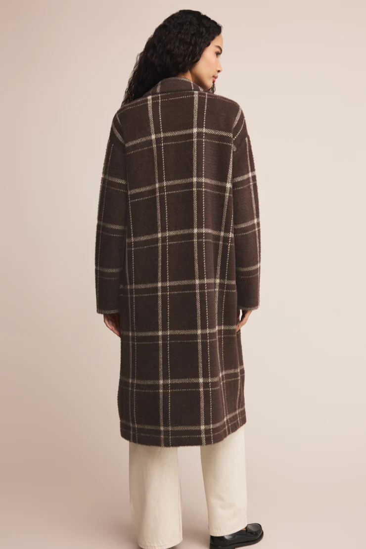 Woman wearing a brown plaid coat against a beige background