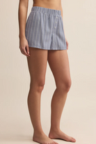 Blue striped shorts worn by a person on a beige background